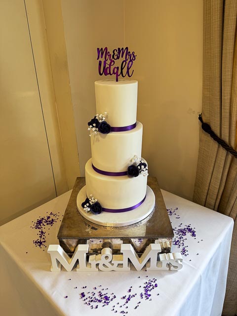 Three tier white wedding cake with purple floral details at Aldwickbury Park Golf Club Harpenden