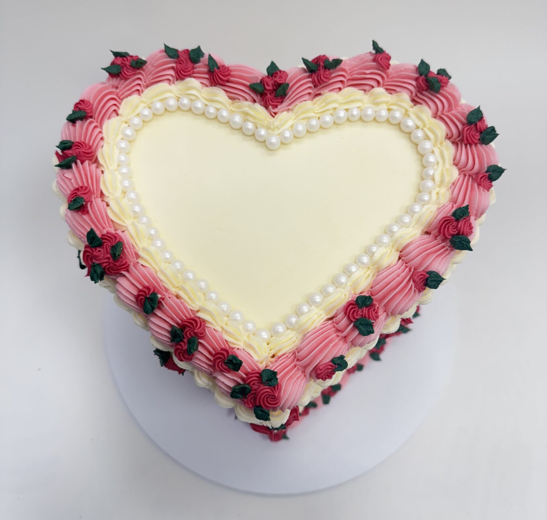 heart cake with piped buttercream, roses and pearls