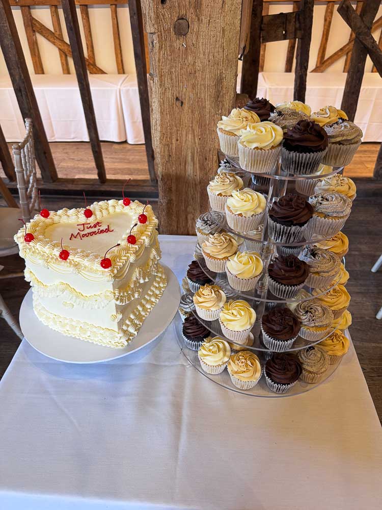 Vintage heart wedding cake with cherries alongside a tower of chocolate and vanilla cupcakes at Tewinbury Farm Hotel