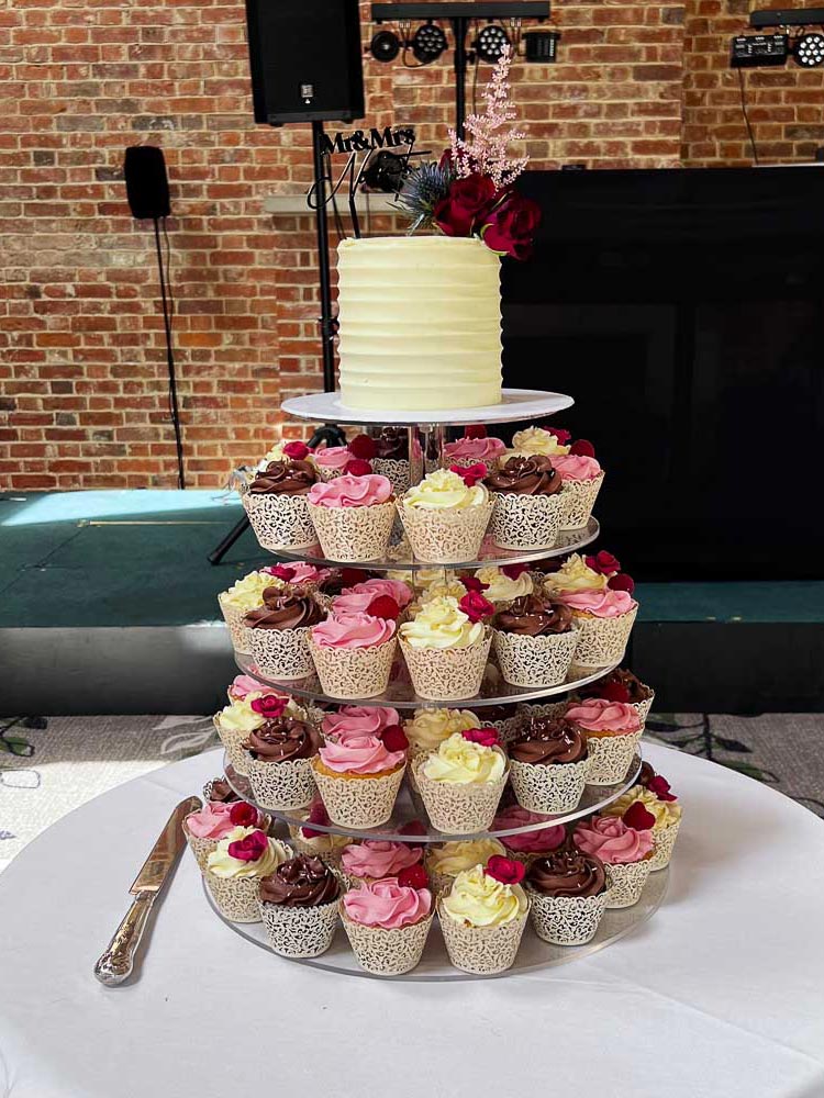 Wedding cupcake tower with pink, chocolate and vanilla cupcakes and a small floral cake at Brocket Hall